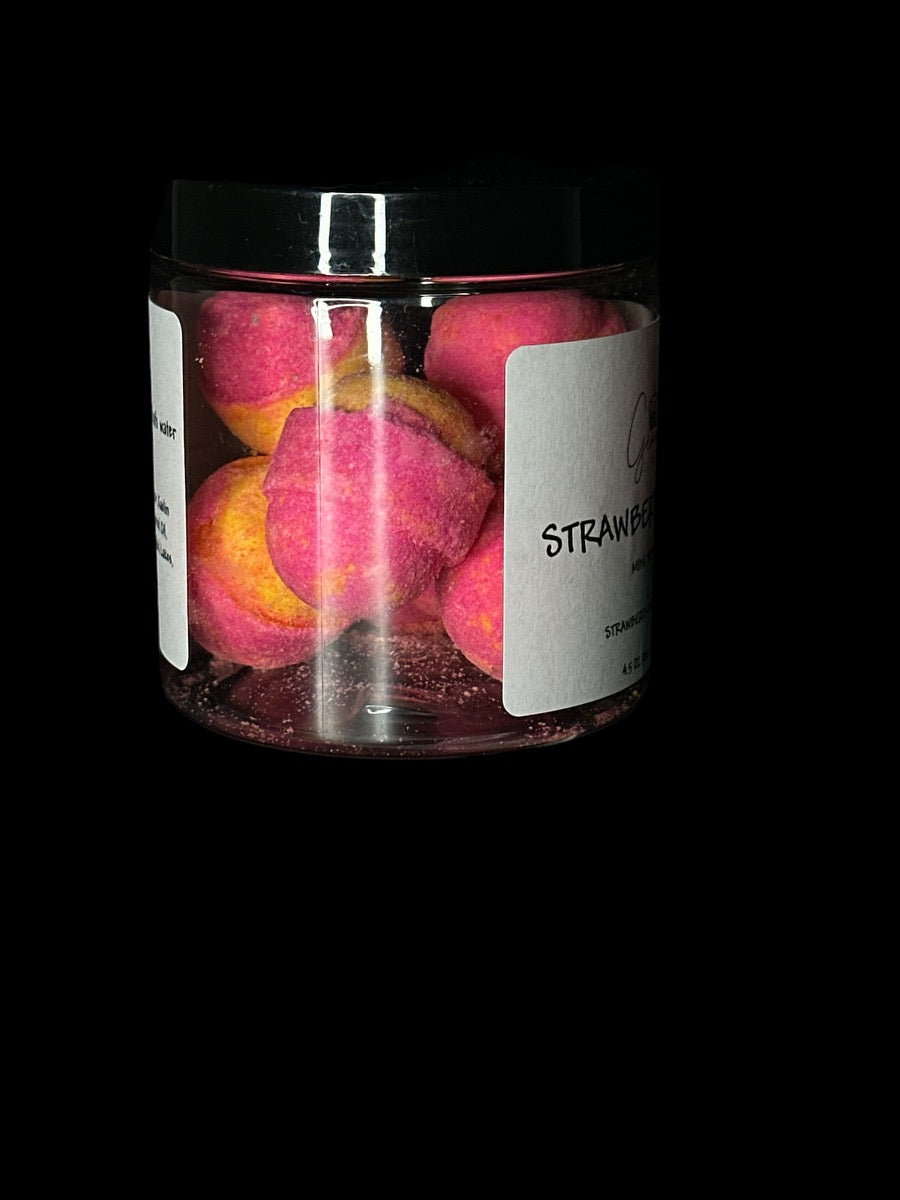 A clear of jar of pink, yellow and orange bath bombs with a black and white ingredient label.